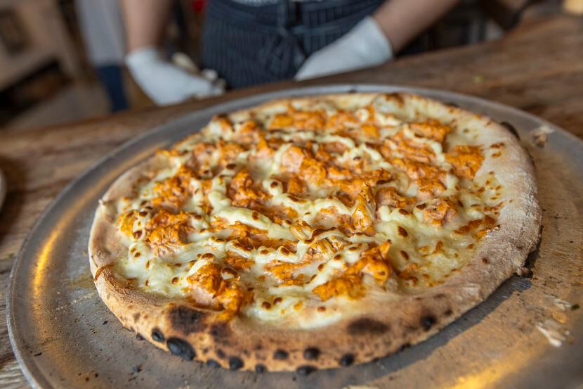 A seasoned chicken with Brazilian style catupiry cheese pizza is seen, fresh out of a wood...
