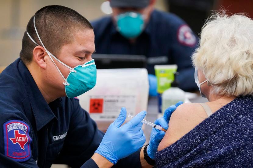 Arlington firefighter Jose Moreno administers the Moderna COVID-19 vaccine to a woman at the...