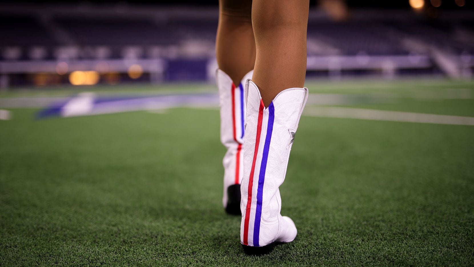 Una porrista de los Cowboys de Dallas modela botas con una raya roja distintiva. Las...