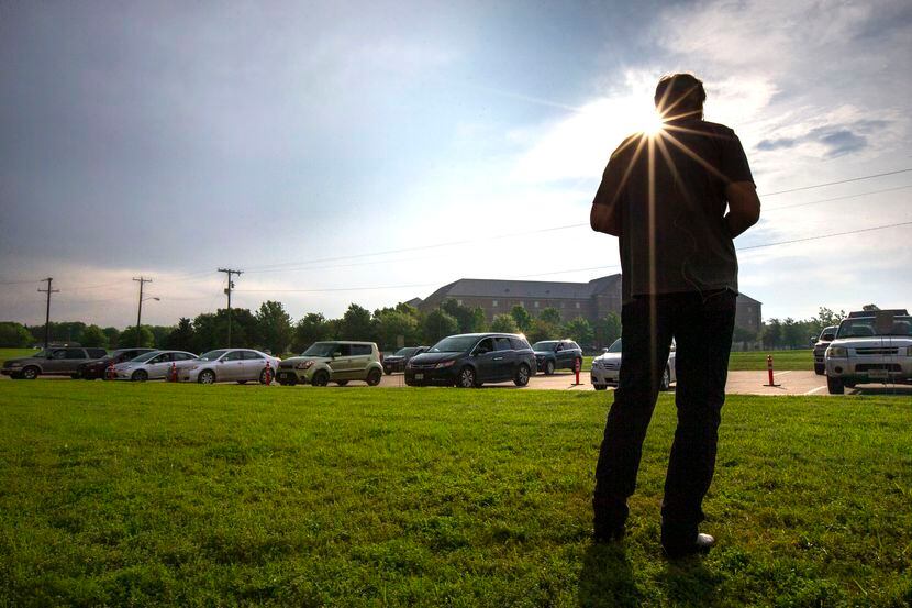 Pastor Bruce Zimmerman broadcasts a prayer service over the radio to attendees parked in...