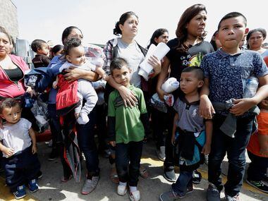 Immigrant women and children wait to enter the bus station after they were processed and...