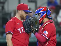 Texas Rangers relief pitcher Ian Kennedy gets a visit from catcher Jose Trevino as he comes...