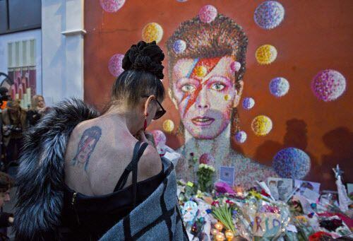 Un mujer deja una ofrenda para el músico David Bowie quien falleció el lunes, a los 69 años....