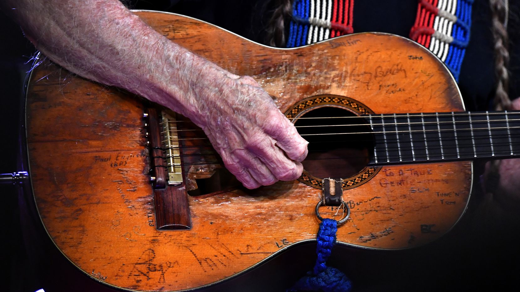 Willie Nelson strums his well-worn guitar, Trigger, during his set at the Outlaws & Legends...