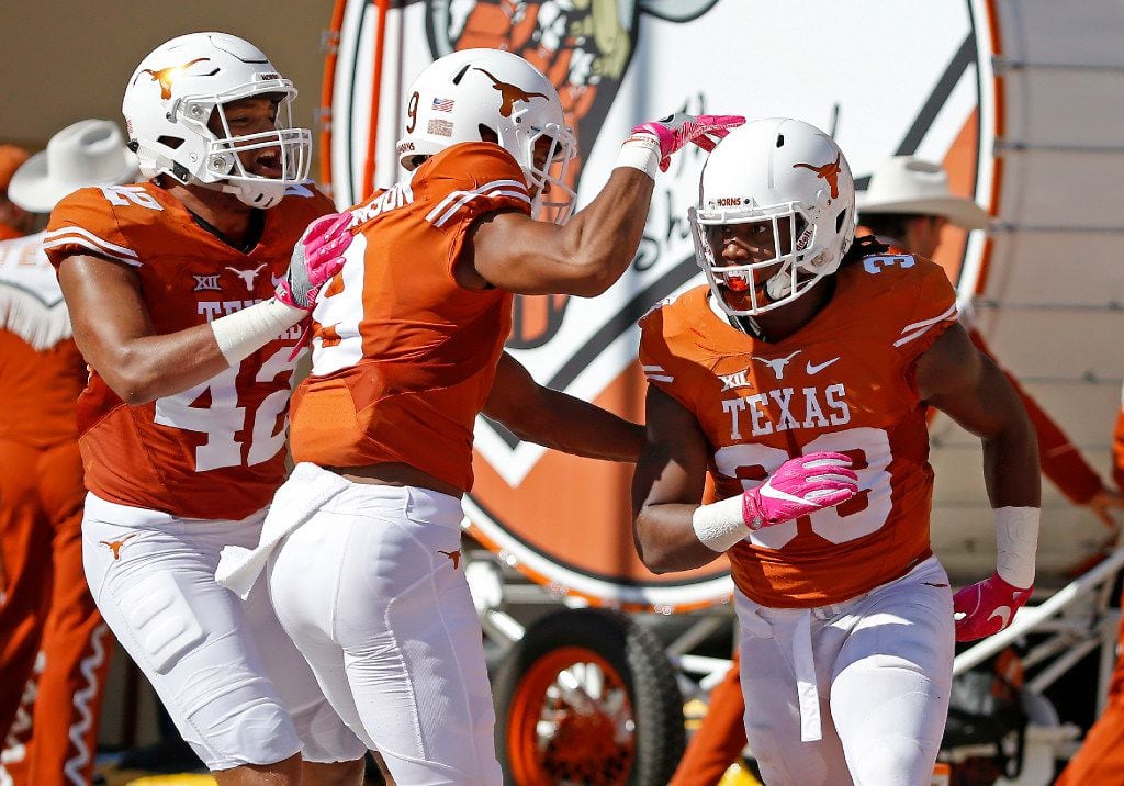 Texas running back D'Onta Foreman (33) is congratulated by wide receiver Collin Johnson (9)...