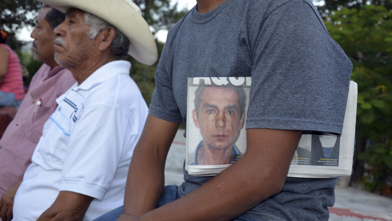 Un hombre sostiene un periódico con la foto del ex alcalde de Iguala, Jose Luis Abarca,...