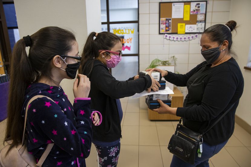 Adlemi Morales (left), 13, and Emeline Morales, 11, grab Wi-Fi hotspots provided by DISD...