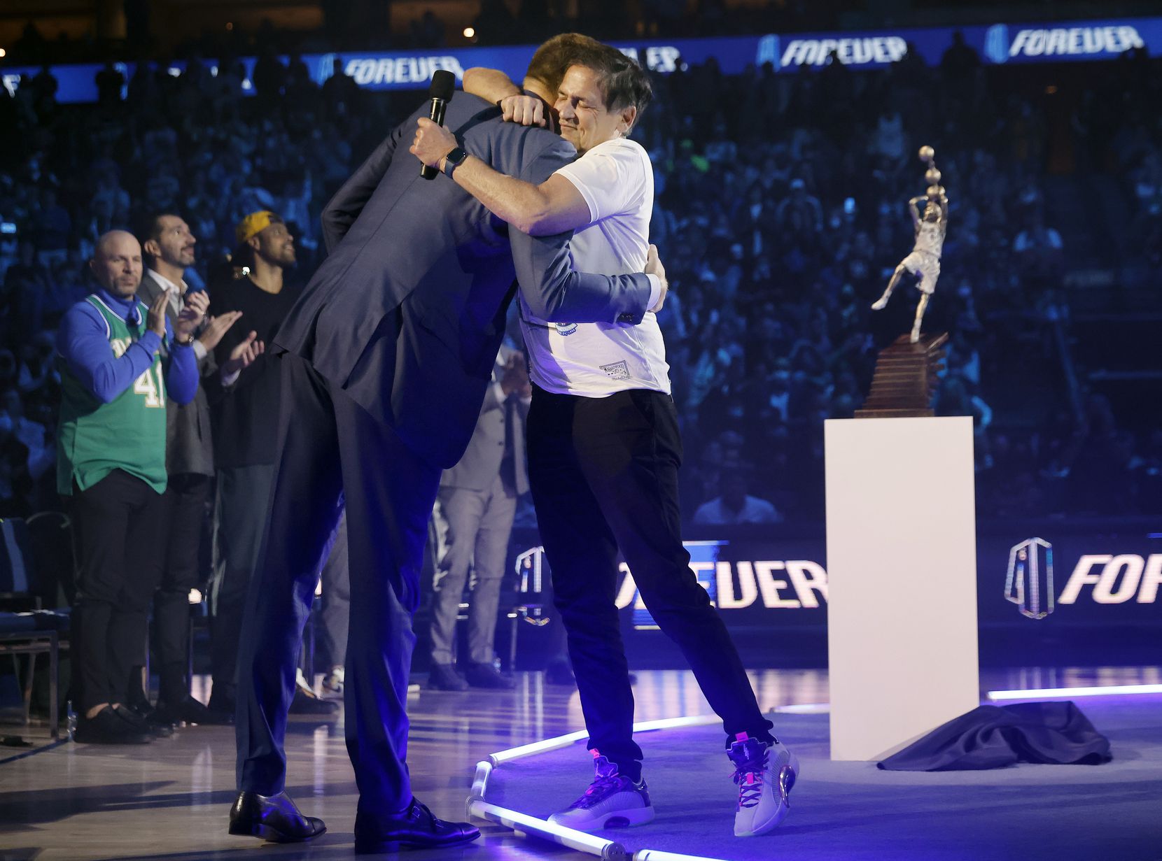 After making some remarks, former Dallas Mavericks All-Star Dirk Nowitzki (left) gives a hug...