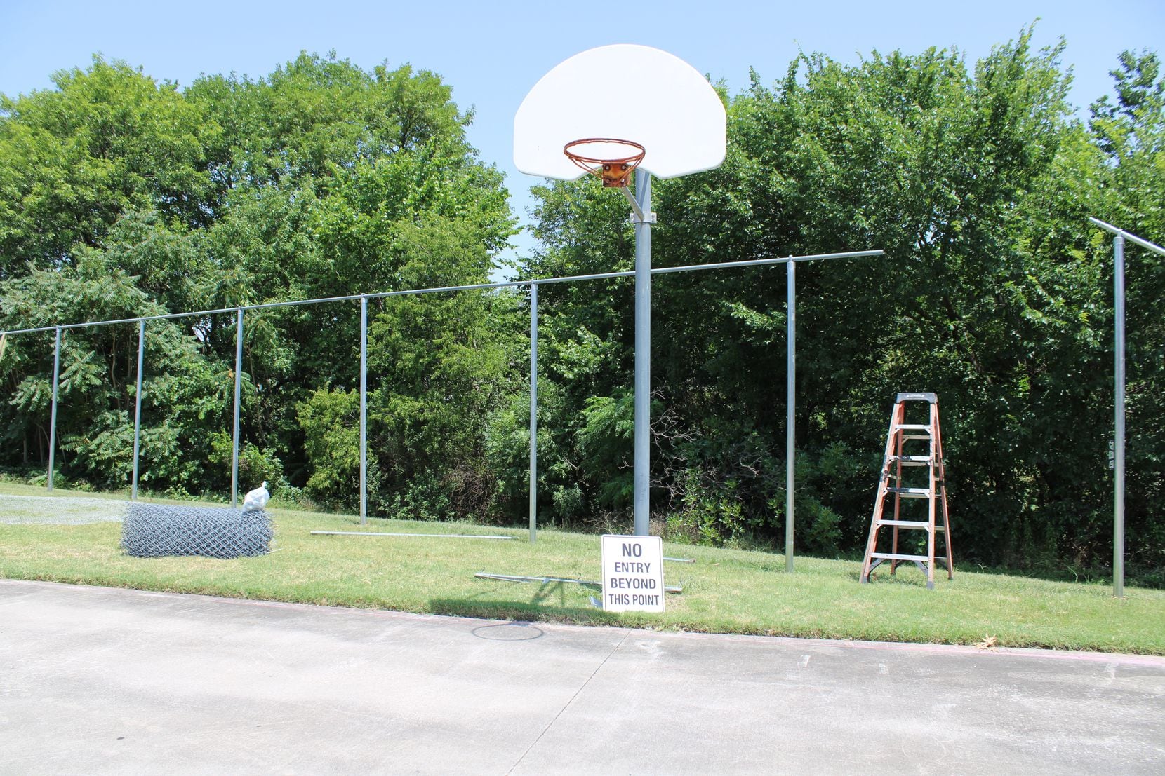 A company placed fencing behind a basketball court at Park Crest Elementary School on July 24. (Sophie Austin/The Dallas Morning News)