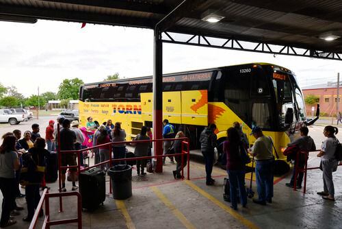 Un grupo de hispanos hace fila para abordar un autobús que se dirige a México desde Dallas.