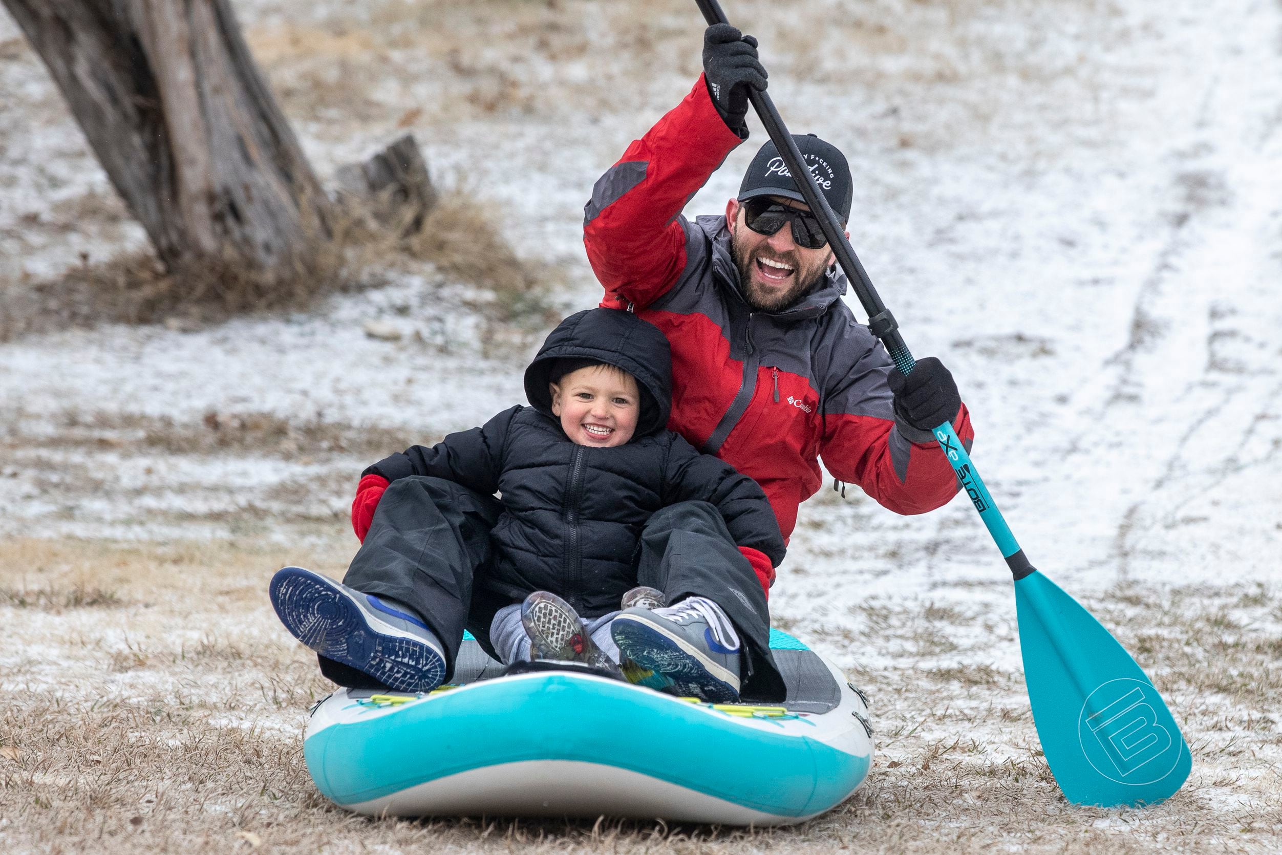 John Bain and his son, Everett, 3, sled down a hill on a paddleboard in the snow at Flag...