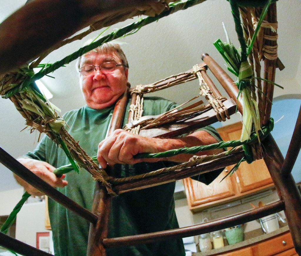 Mike Turrentine is framed by a child's rocking chair as he reweaves a seat in his Garland home.