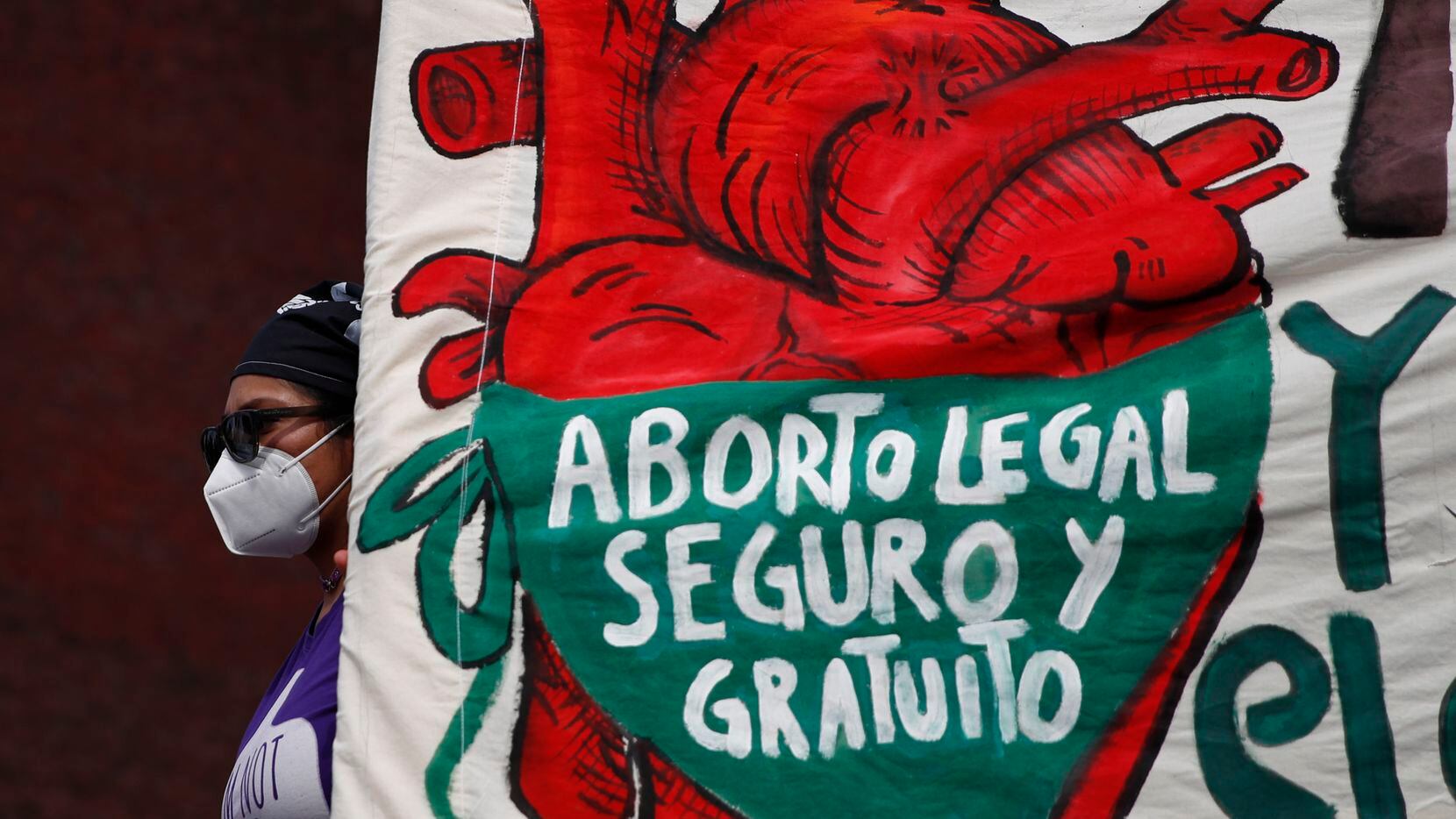 FILE - A woman holds a banner reading in Spanish, "Legal, safe, and free abortion" as...