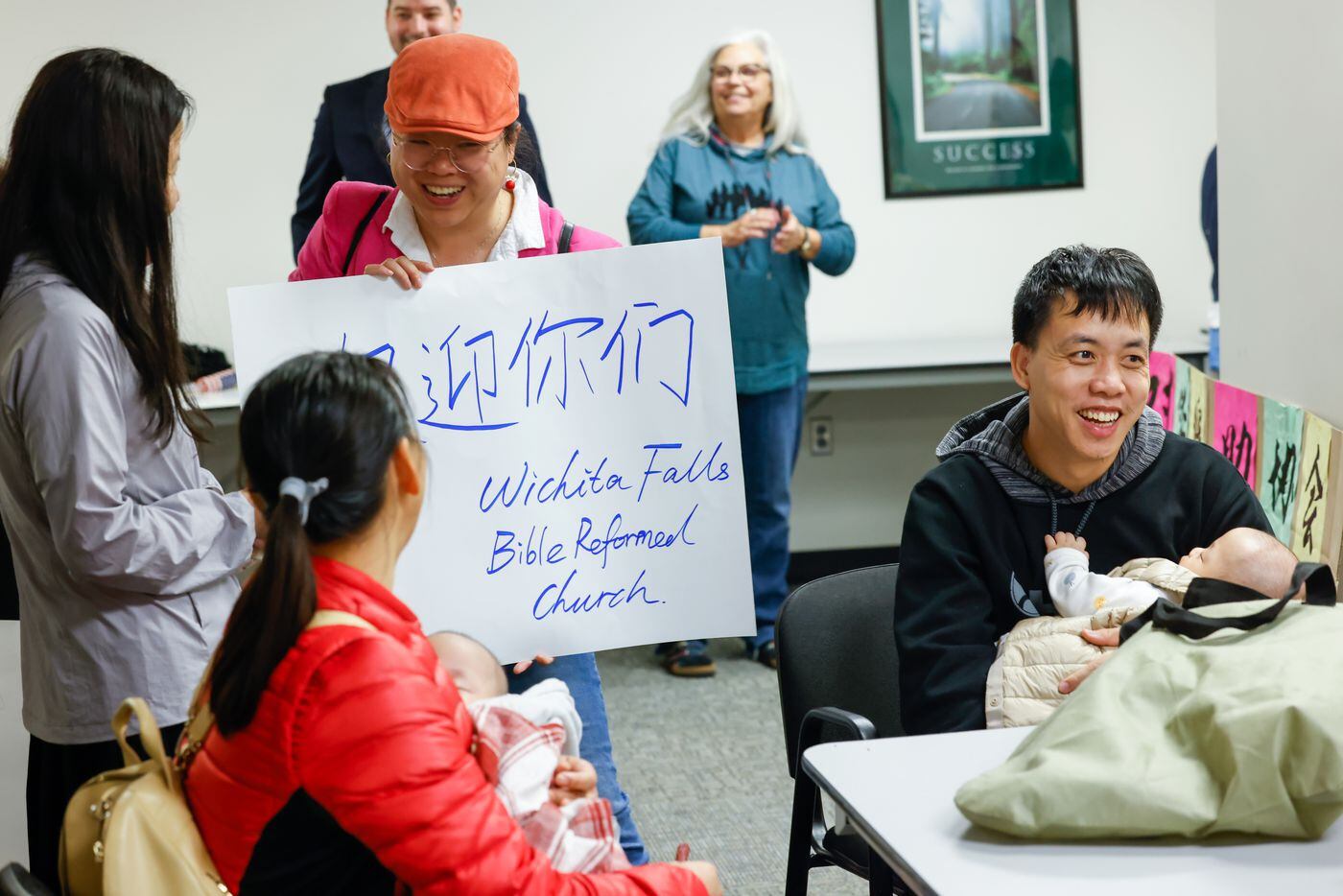 Wichita Falls Bible Reformed Church member Min Huang (center) speaks with asylum-seekers...
