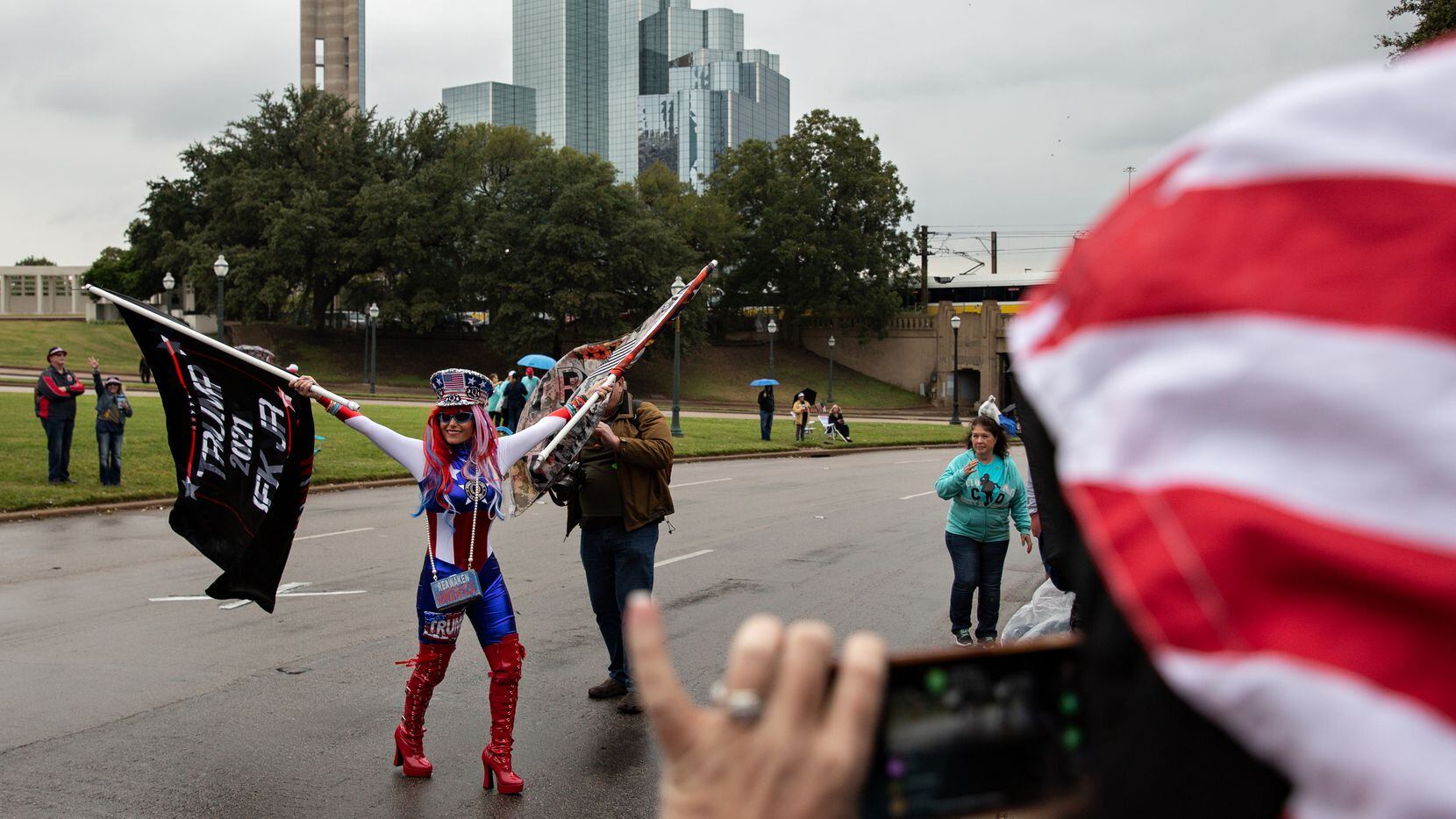 Micki Larson-Olson waves two Trump flags in the street of Dealey Plaza during a QAnon...