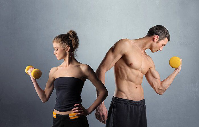Young man and woman in sport clothes lifting weights