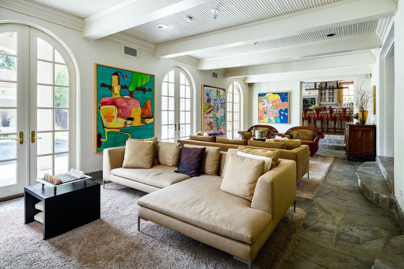 A sunroom and formal living room lead into a spacious family room with three sets of French...