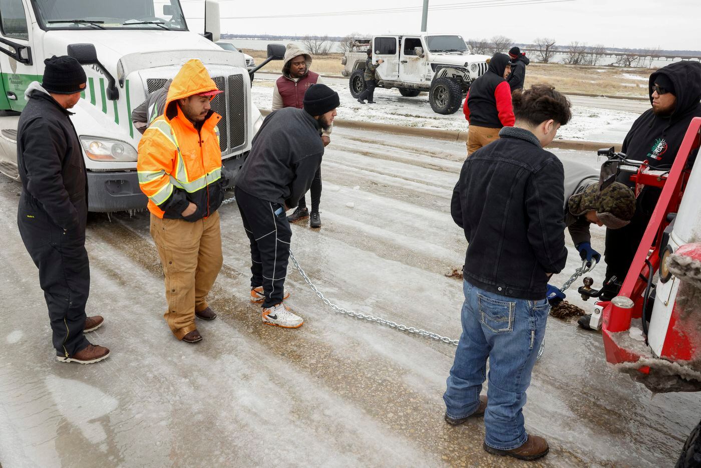 Members of the Carnales Off Road Jeep club connect a tow chain to a semi-truck and Jeep on...
