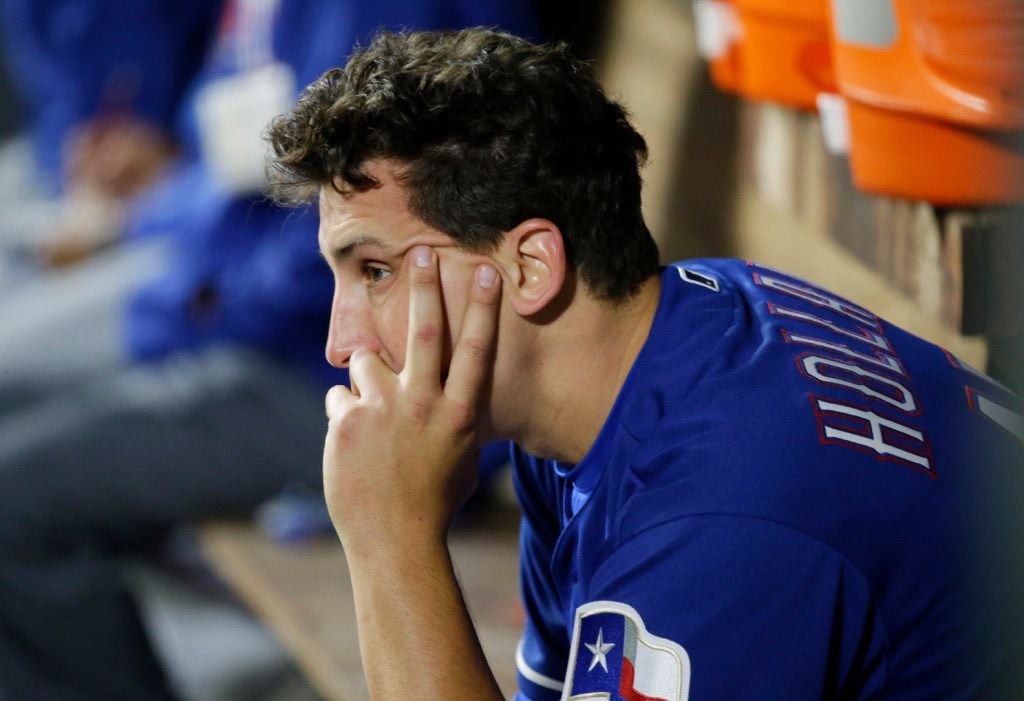 Texas Rangers starting pitcher Derek Holland sits in the dugout after being pulled from a...