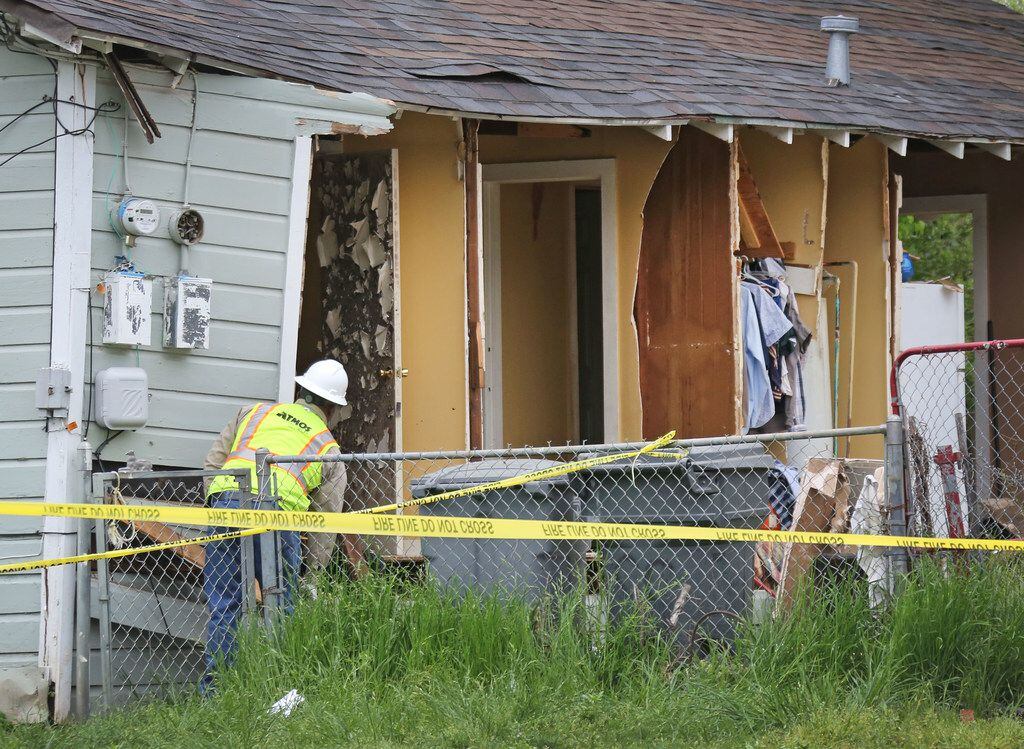 An Atmos worker investigates a house explosion at 3700 Spring Avenue in Dallas, near Fair...