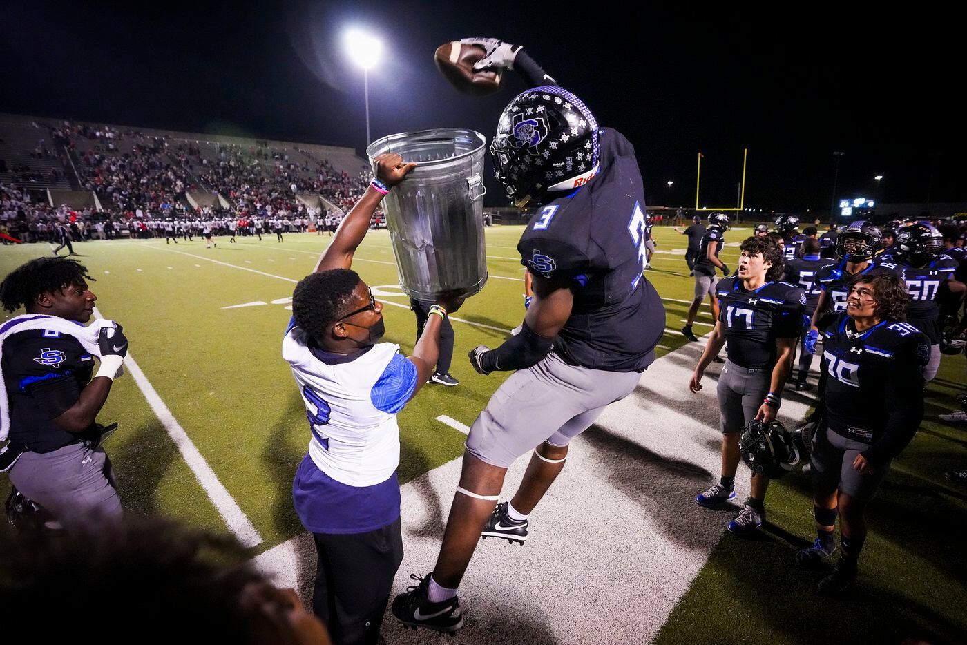 Mansfield Summit defensive back Ahmaad Moses (3) celebrates by dunking a football into a trash bin on the sideline after intercepting a Colleyville Heritage pass during the second half of the Class 5A Division I Region I final on Friday, Dec. 3, 2021, in North Richland Hills, Texas. (Smiley N. Pool/The Dallas Morning News)