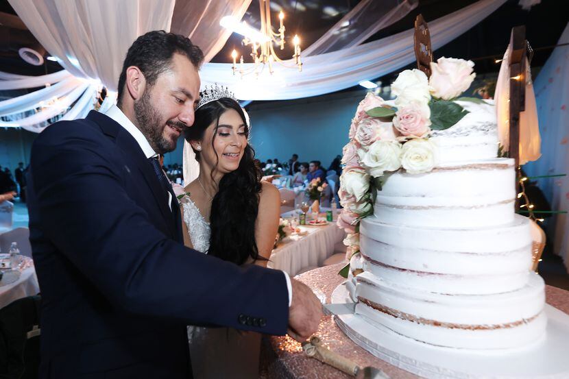 Daniela Betancourt, de 26 años, junto a Martin García, de 35, corta el pastel de su boda, el...