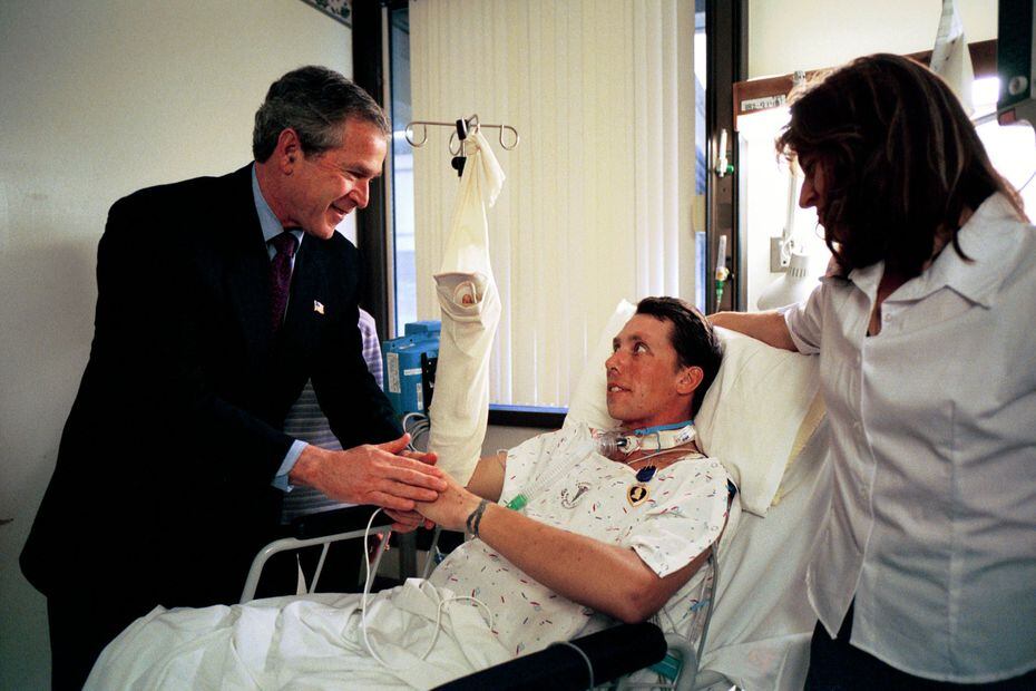 President George W. Bush shakes hands with Army SFC Thomas Douglas of Fayetteville, NC, after presenting him with the Purple Heart at Walter Reed Army Medical Center on April 11, 2003. At right is Douglas' wife, Donna Douglas.