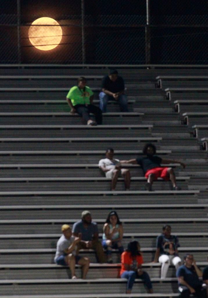 A full moon rises over Irving High fans in the stands during the first half of their high...