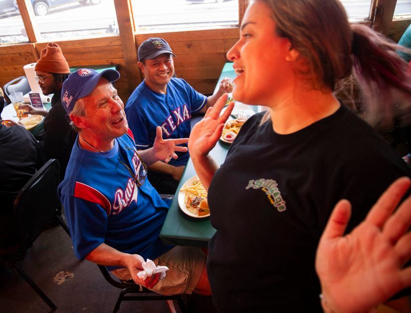 (From left) Dan Fisher and Duy Ly wear their Texas Rangers attire as they chat with waitress...