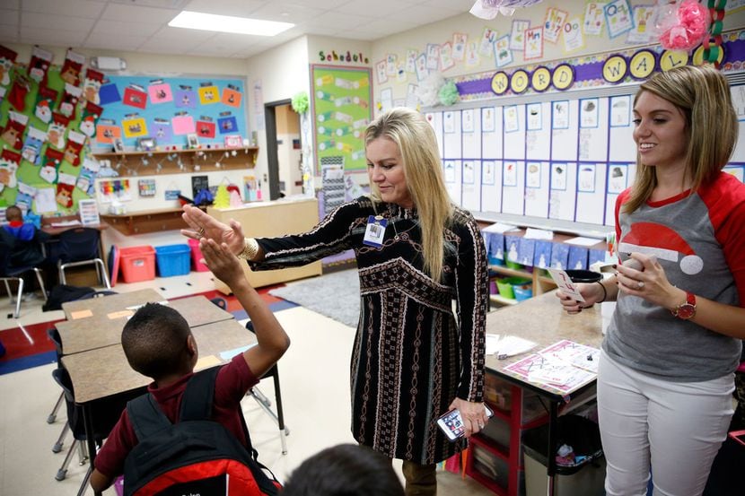 First grader Calen Simms, 6, gives principal Aimee Lewis a high five after correctly...