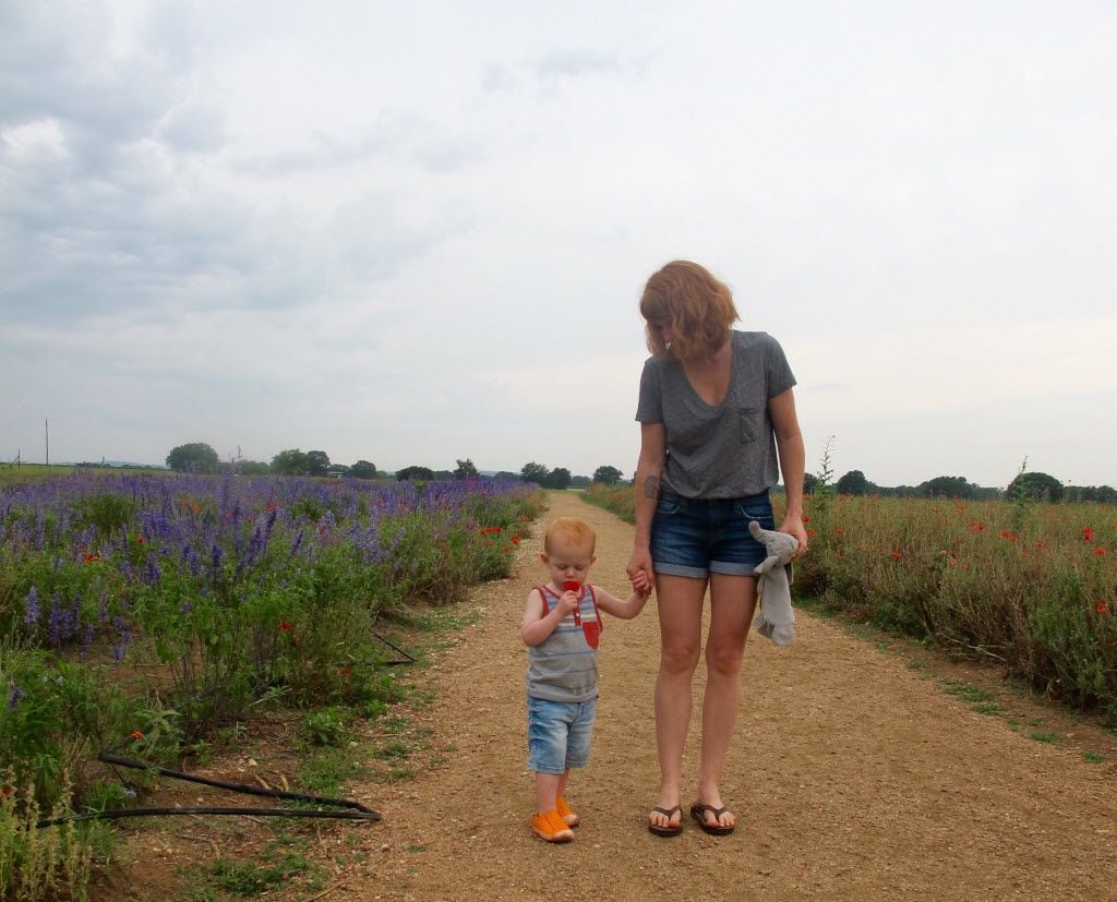 A mom and her toddler walk along the flower garden path at Becker Vineyards.