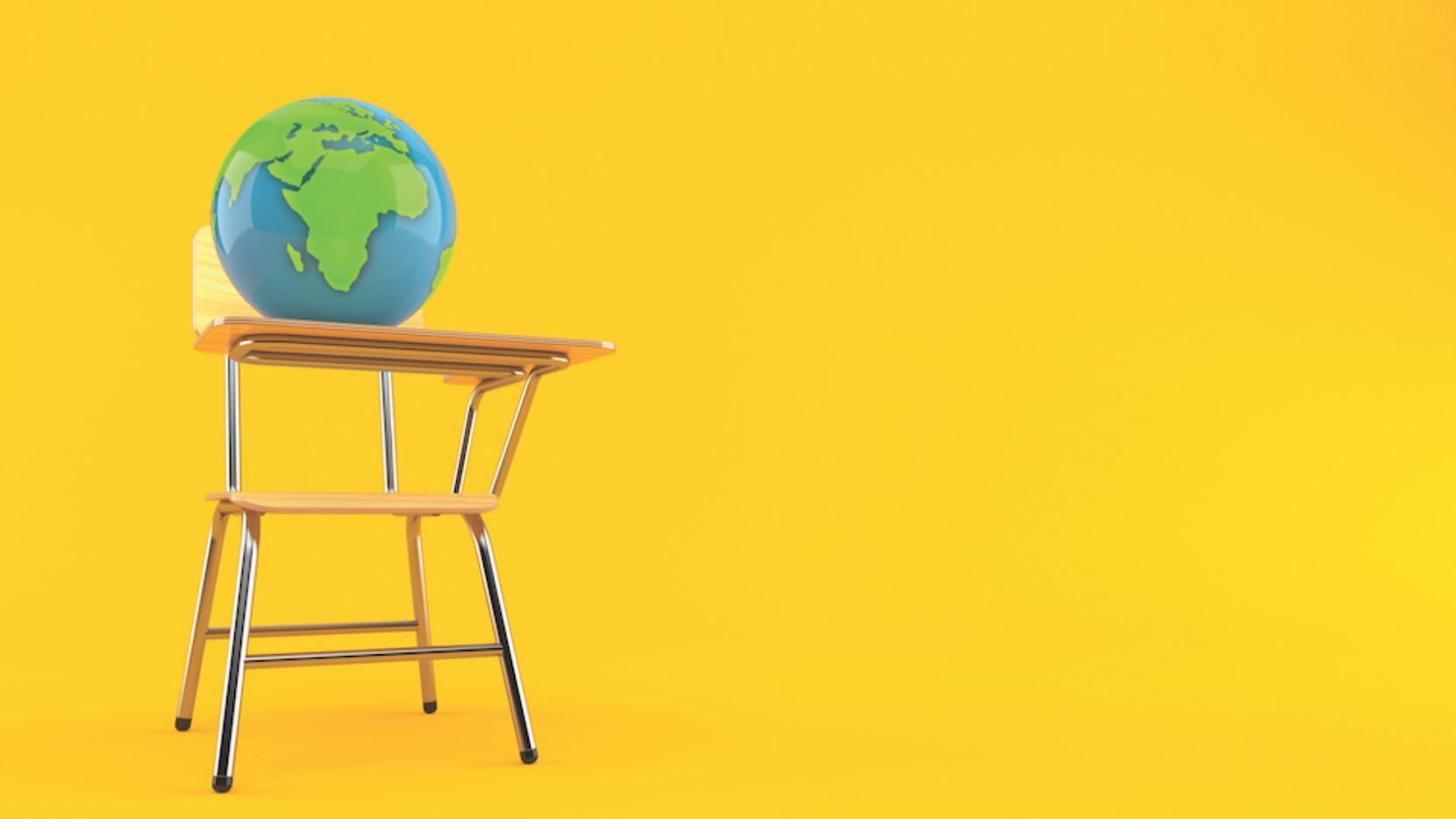 A globe sits on top of a school desk against a yellow background.