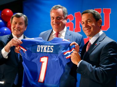SMU president Gerald Turner (left) and athletic director Rick Hart (right) hand new SMU football coach Sonny Dykes his jersey at The Miller Event Center at SMU in Dallas on Dec. 12, 2017.  (Nathan Hunsinger/The Dallas Morning News) ORG XMIT: DMN1712121153012620