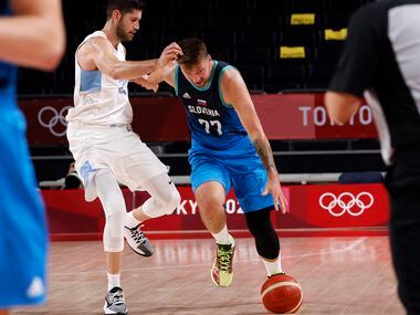 Slovenia’s Luka Doncic (77) dribbles down the court as he is guarded by Argentina’s Patricio...