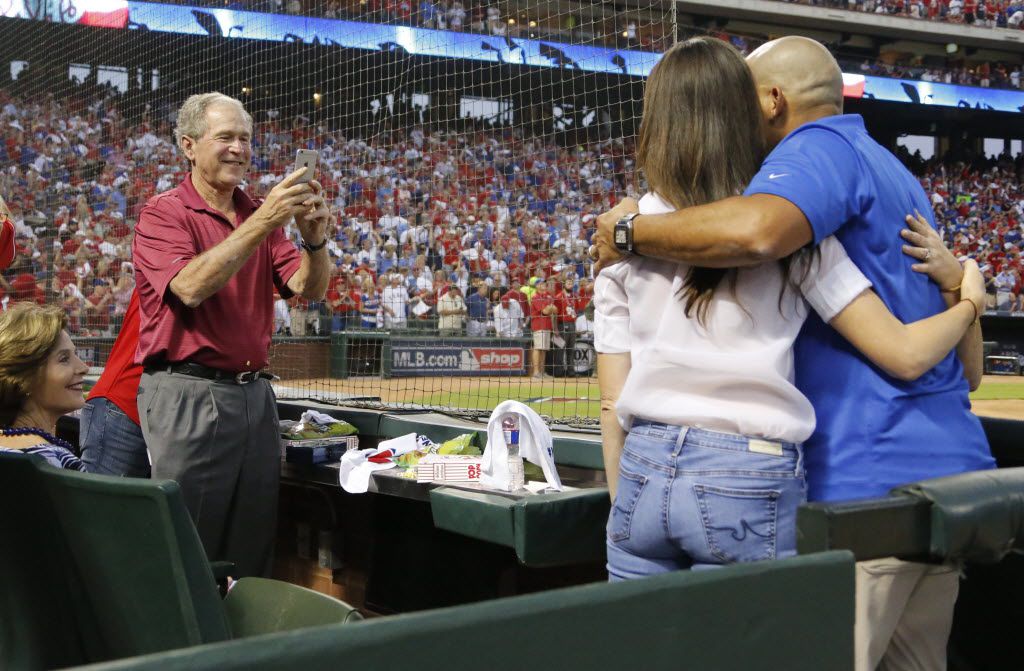 Former President George W. Bush takes a photo of his daughters with Rangers legendary catcher Ivan "Pudge" Rodriguez before Game 3 of the ALDS between the Texas Rangers and the Toronto Blue Jays at Globe Life Park in Arlington, Texas on Sunday, October 11, 2015.