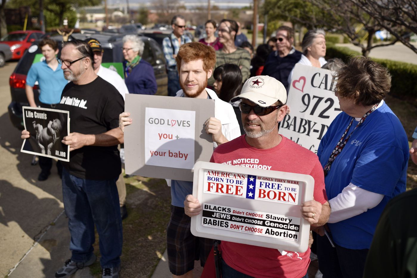 Ethan Moon, 24, (center) of Dallas and Bobby Pope, 50, (right) of Forney held signs Saturday...