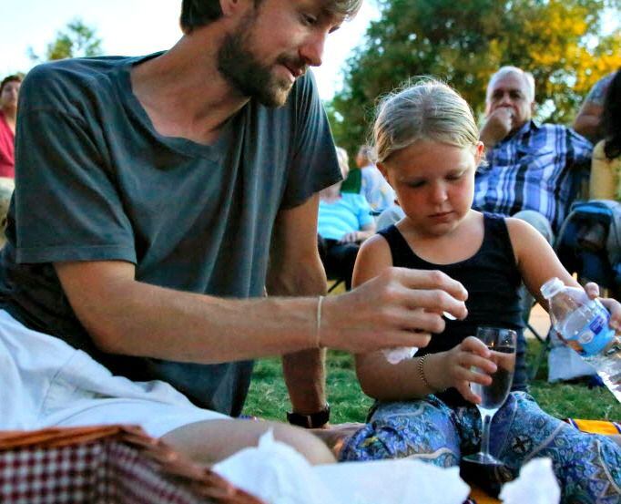 Avery Heinz, 6, pours a glass of water with Andrew Readinger during the Levitt Pavilion's...