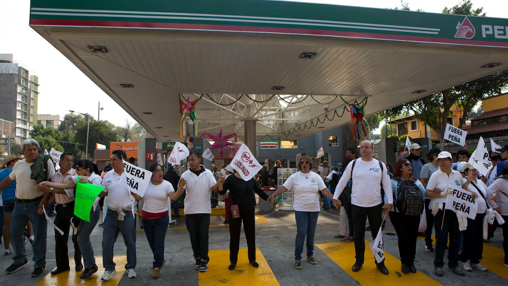Personas forman una cadena humana en una gasolinera en la Ciudad de México para protestar...