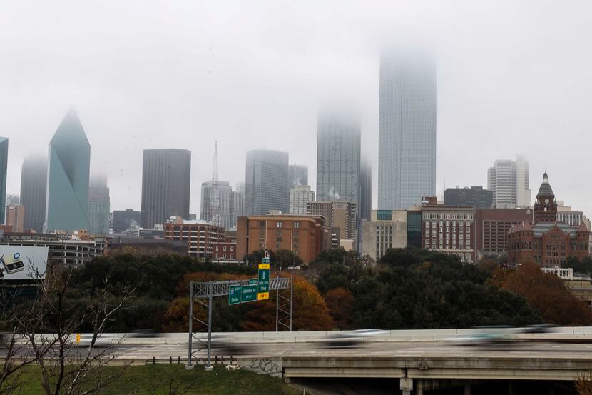 Cars speed down Interstate 35 East as  fog looms over the city skyline of Dallas, Wednesday,...