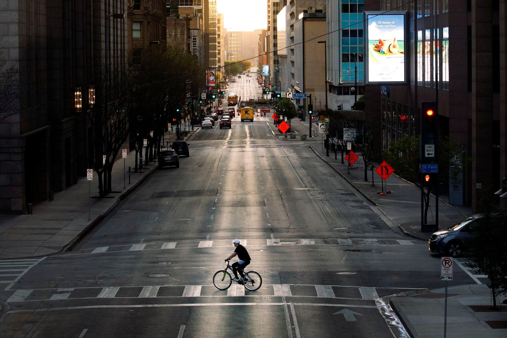 With very few cars on the street, a cyclist peddles across Elm St. in downtown Dallas, Wednesday evening, March 25, 2020.  There's less traffic than normal after Judge Clay Jenkins ordered a shelter-in-place due to coronavirus.  (Tom Fox/The Dallas Morning News)