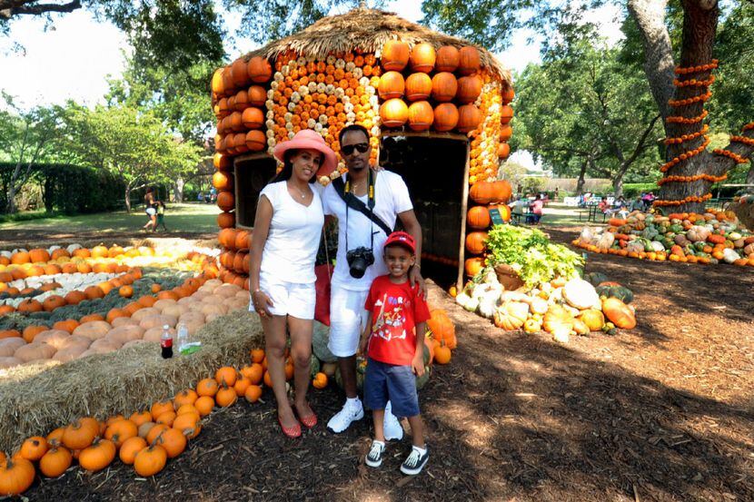 A family poses for a photo in the Pumpkin Village at the Dallas Arboretum and Botanical Garden.