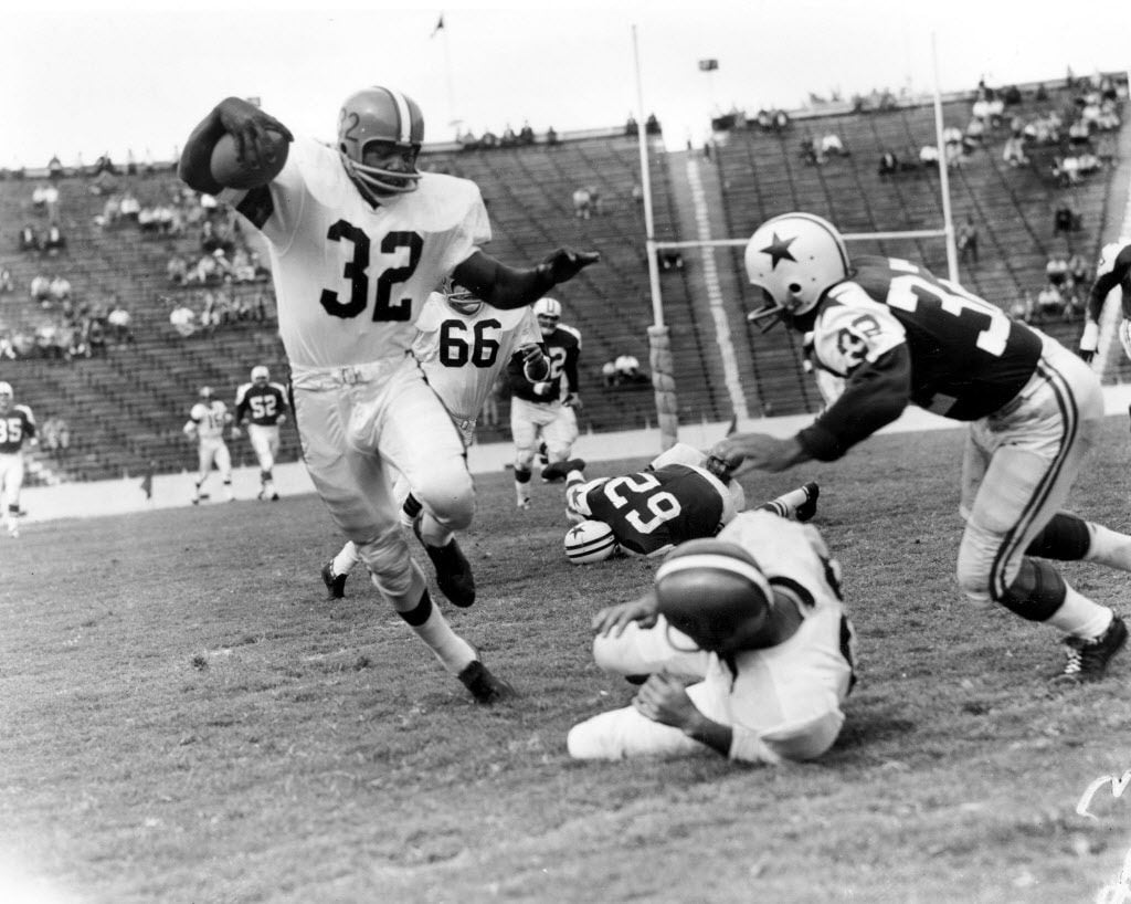 Jim Brown (32), fullback of the Cleveland Browns, rounds at right end after receiving pass...