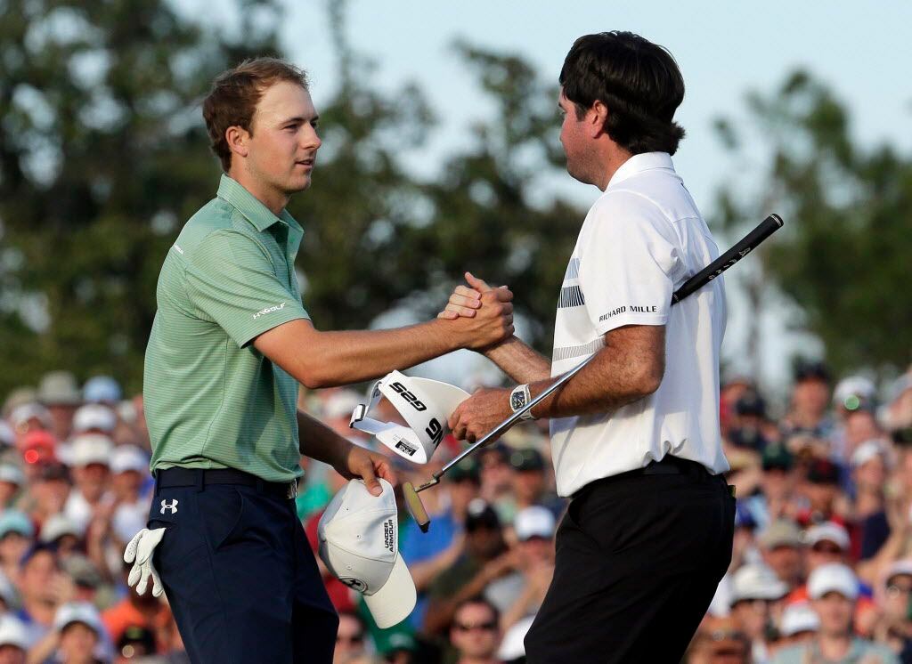 Bubba Watson, right, shakes hands with Jordan Spieth after winning the Masters golf...
