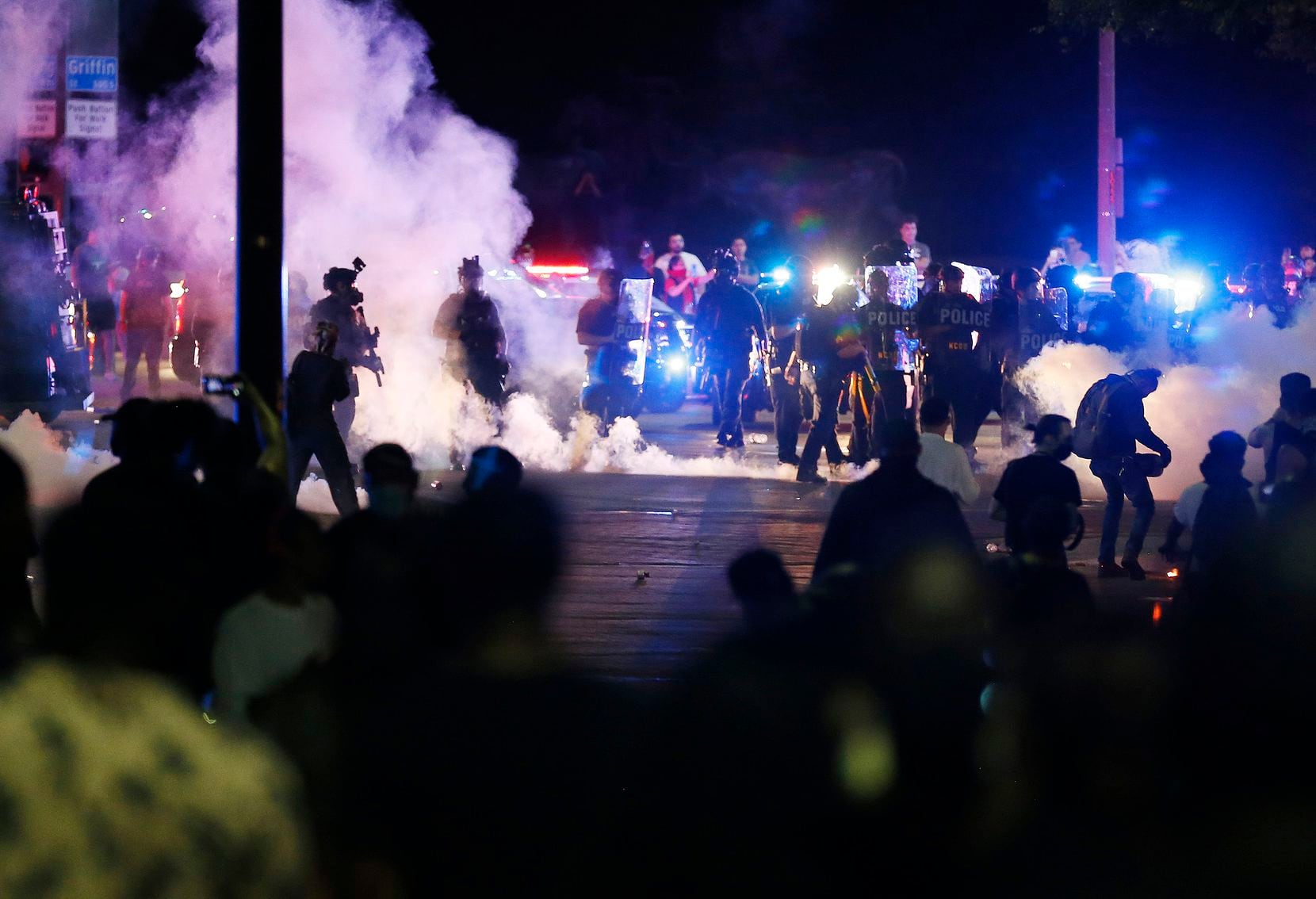 Tear gas fills the air as Dallas police attempt to disperse the crowd along Young Street and...