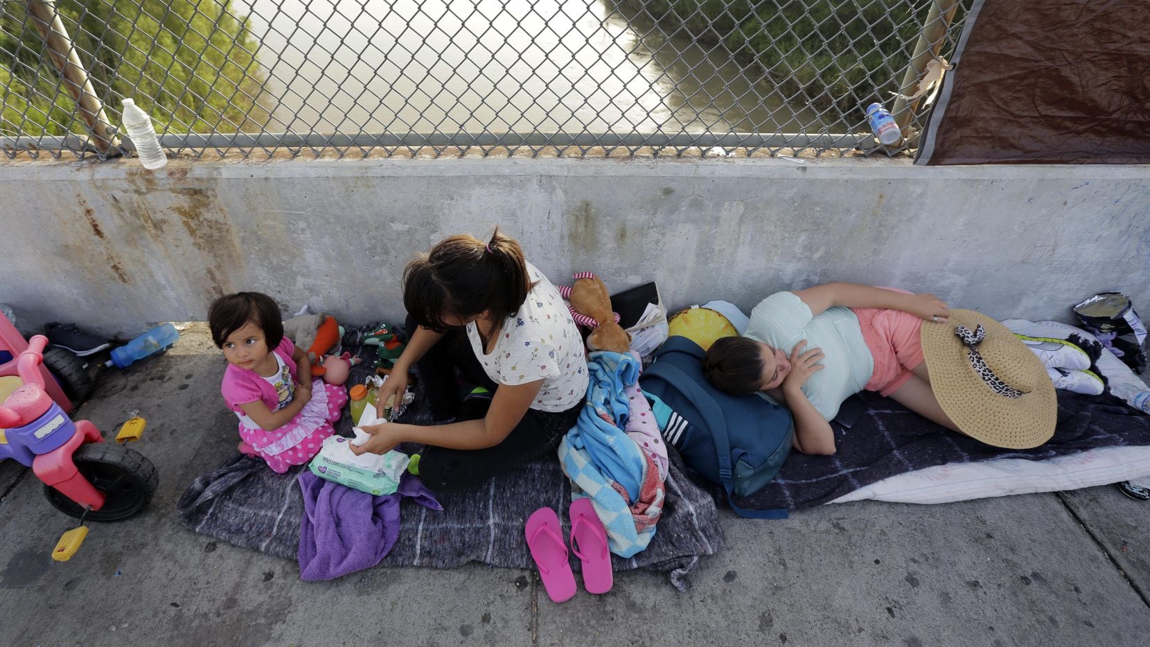 Inmigrantes de Cuba y Guatemala que buscan asilo en Estados Unidos esperan en el Puente...