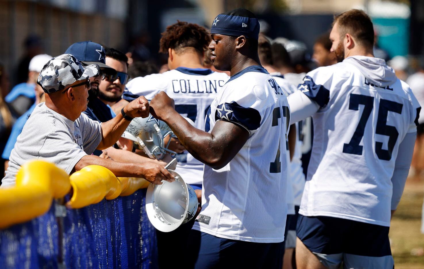Dallas Cowboys rookie offensive tackle Tyler Smith (73) gives a fist bump to a volunteer...